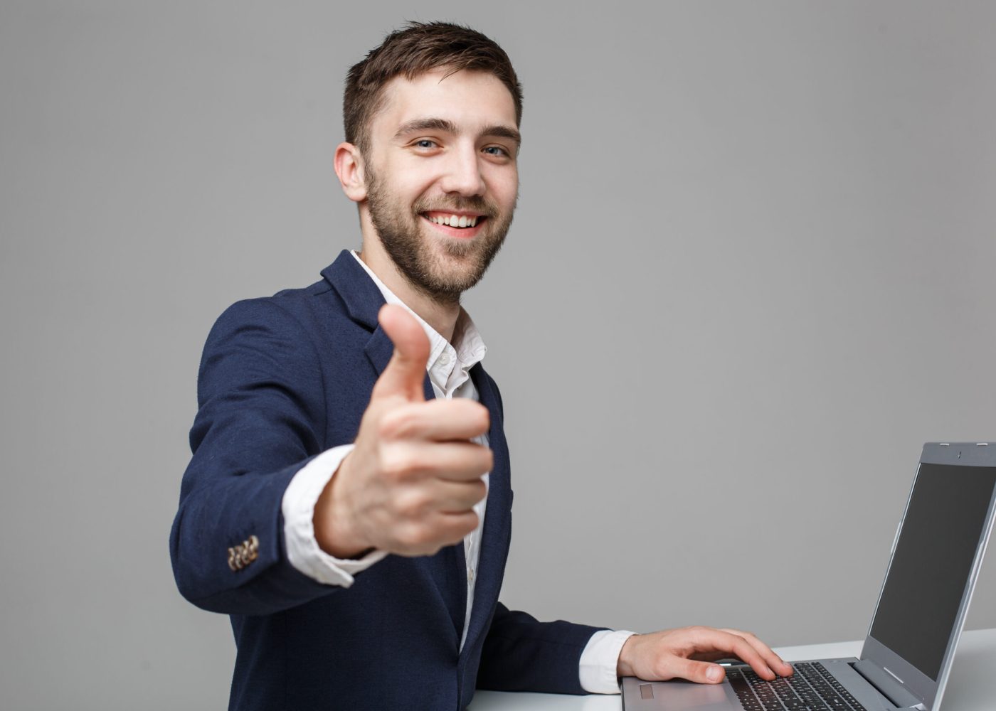 Business Concept - Portrait Handsome Business man showing thump up and smiling confident face in front of his laptop. White Background.Copy Space.