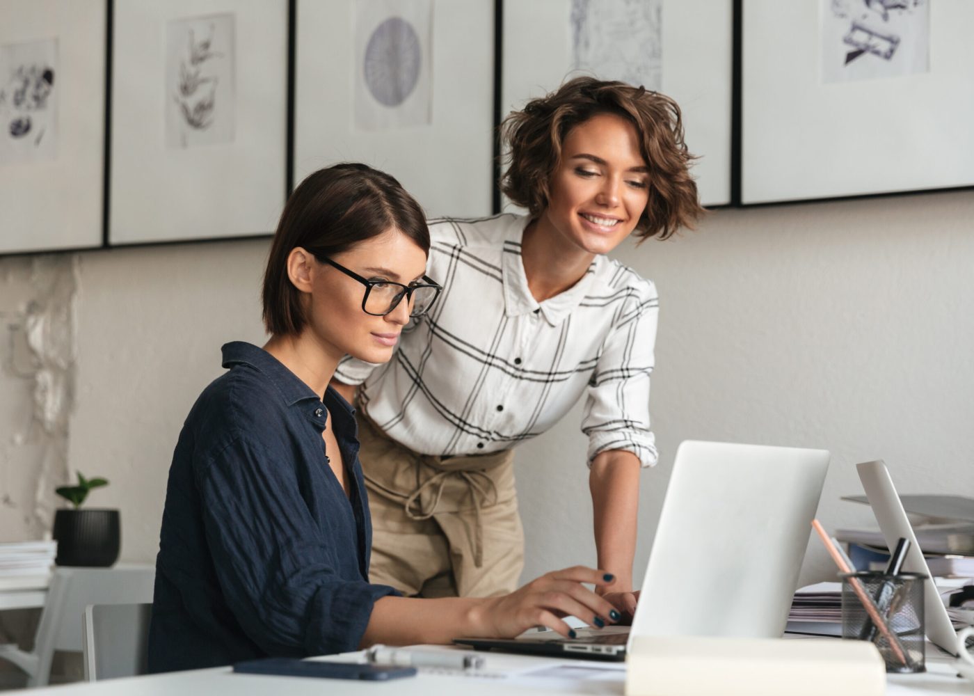 Side view of two women are discussing something by the table in co working office