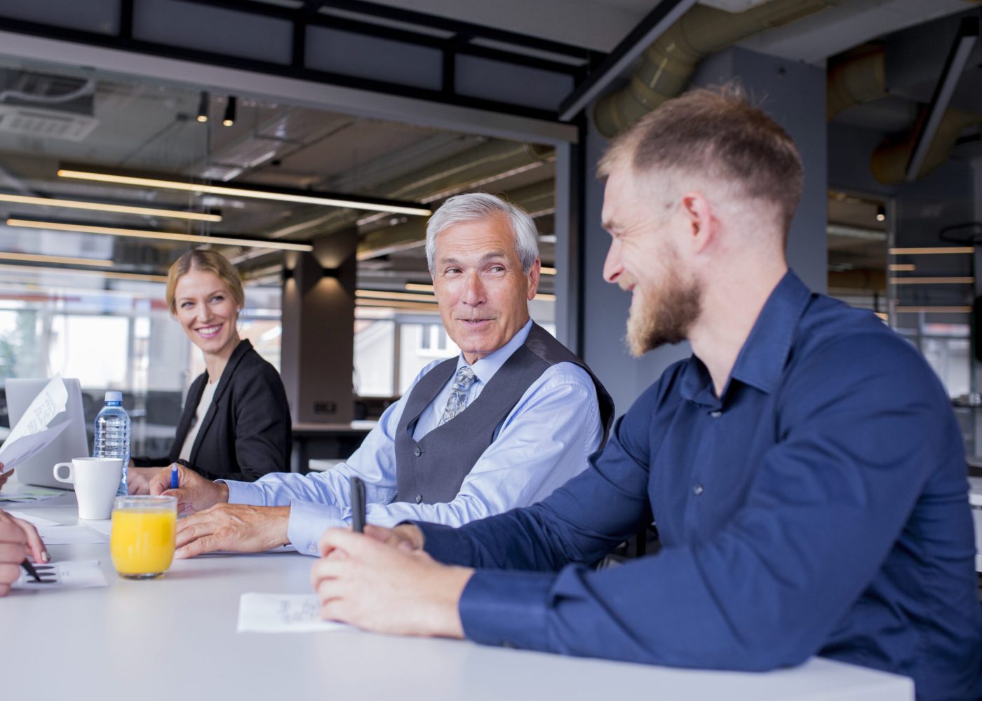 smiling-senior-manager-with-his-employees-sitting-together-meeting