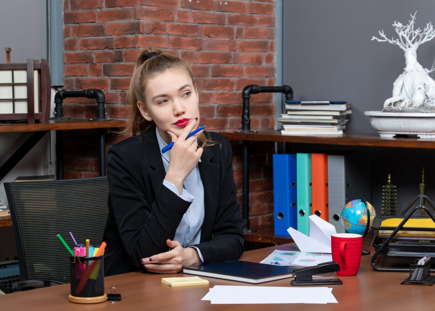 top-view-young-confused-female-office-worker-sitting-her-desk-posing-camera